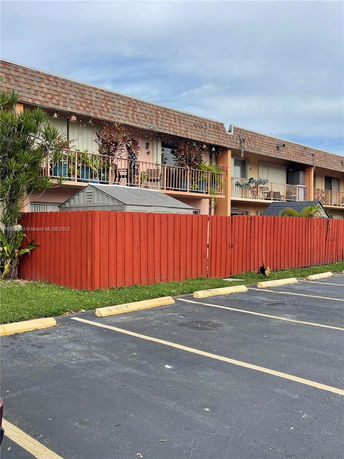 Front view of a two-story building with a parking area in front.