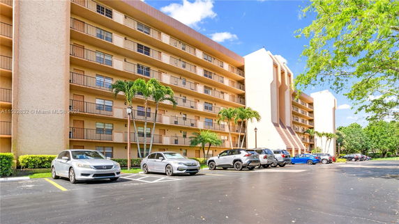 Front view of a multi-story residential building with balconies and parking area.
