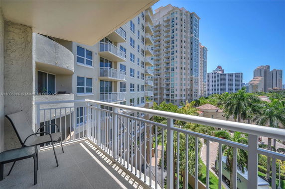 View from a balcony overlooking adjacent high-rise buildings and palm trees.