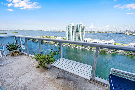 Balcony view overlooking a body of water and a cityscape in the distance.