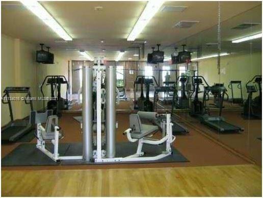 Interior view of a gym with exercise equipment and mirrors.