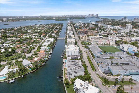 Aerial view of a coastal city with waterways, residential areas, and distant cityscape.