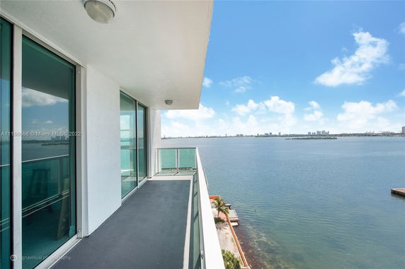 Panoramic view from a balcony overlooking a body of water and distant city skyline.