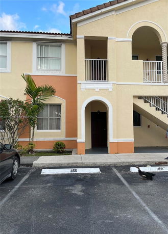 Front view of a two-story apartment building with an arch and staircase.
