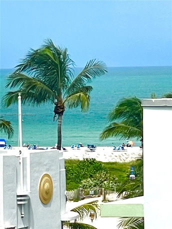 View of the ocean with palm trees and beach visible from a building.