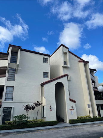 Front view of a multi-story building with beige exterior and red-tiled roof.