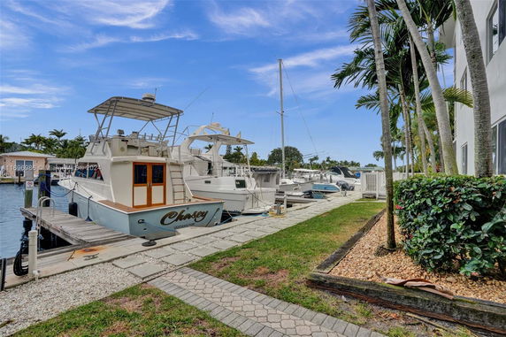 Docked boats near a building with palm trees and a clear sky.