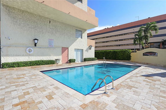 Outdoor swimming pool area next to a building wall with decorative textured surface.