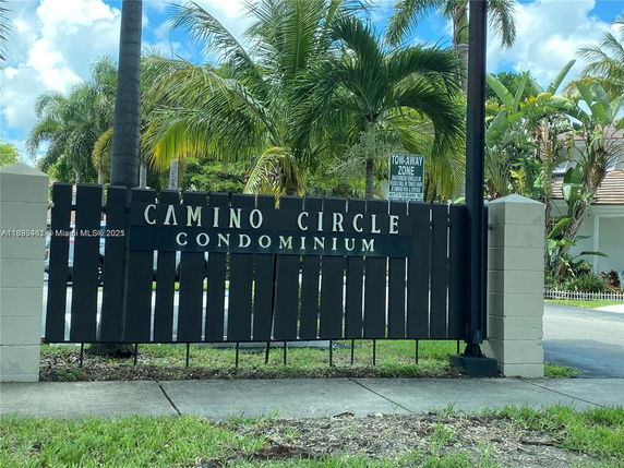 Entrance sign of Camino Circle Condominium with palm trees in the background.