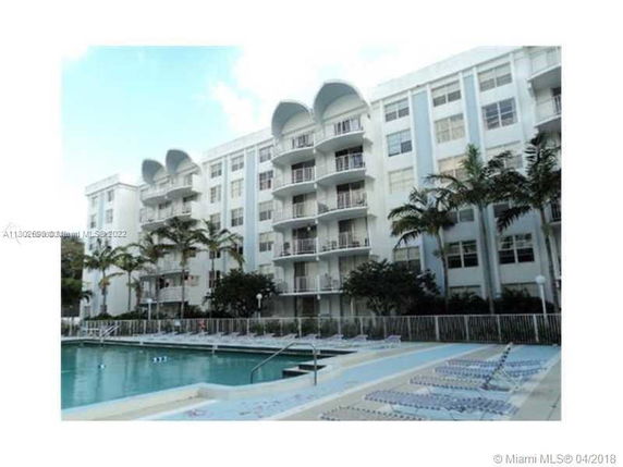 Exterior view of a multi-story residential building with a swimming pool in front.