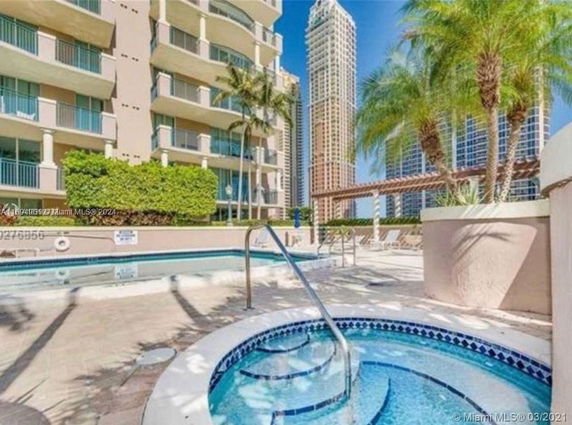 View of a multi-story building with balconies and a pool area in the foreground, surrounded by other tall buildings.