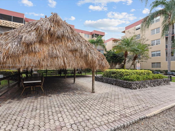 Outdoor view of a residential area with a thatched-roof structure and surrounding apartment buildings.