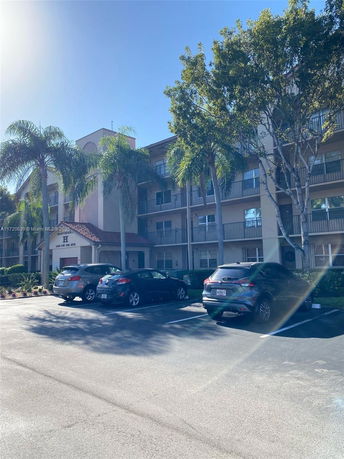 Front view of a multi-story residential building with a parking area.