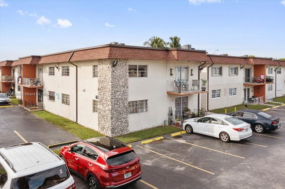 Front view of a two-story apartment building with balconies and parking area.