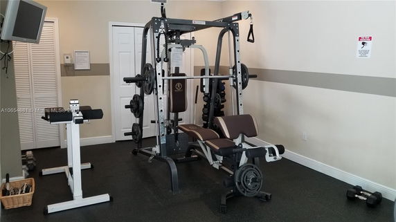 Indoor gym area with exercise equipment including a weight machine and dumbbells.