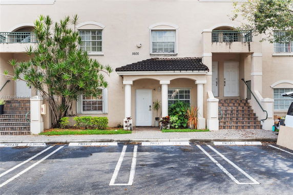 Front view of a two-story residential building with a tiled roof and stairs leading to the entrance.