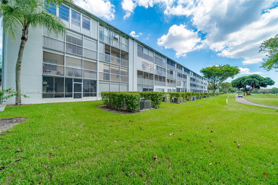Side view of a multi-story residential building with balconies and glass windows.