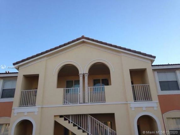 Front view of a two-story building with arched balconies and a tiled roof.