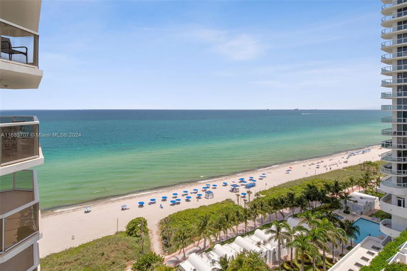 Panoramic view of the ocean from a high-rise building with visible beach umbrellas and sea.