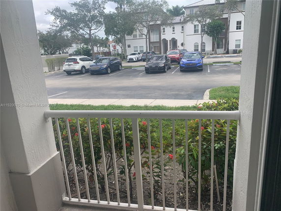 View from a balcony overlooking a parking area with several cars parked.