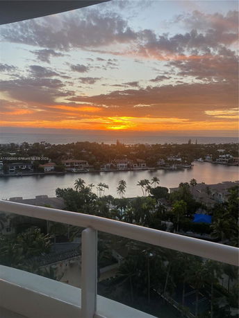 Panoramic view of a sunlit horizon with palm trees and water bodies seen from a building.