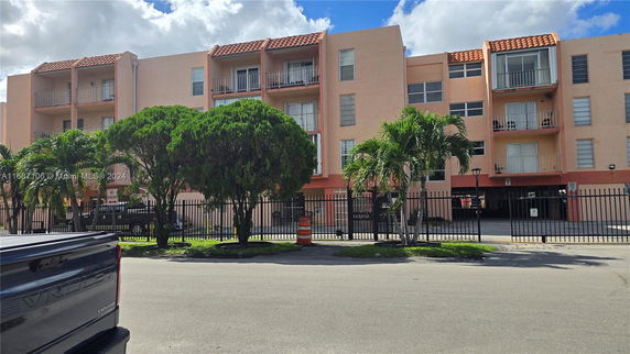 Front view of a multi-story residential building with balconies and a gated entrance.
