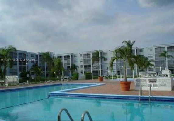 Outdoor swimming pool area with residential buildings in the background.