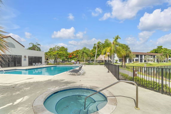 Outdoor swimming pool with lounge chairs and a small round hot tub adjacent.