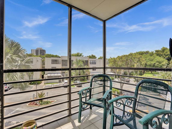 View from a balcony with two chairs overlooking a residential area and greenery.