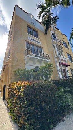 Front view of a multi-story building with beige stucco walls and a sign reading 'The Lincoln'.