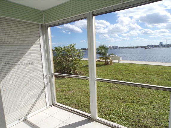 View from a screened porch overlooking a body of water and distant city skyline.
