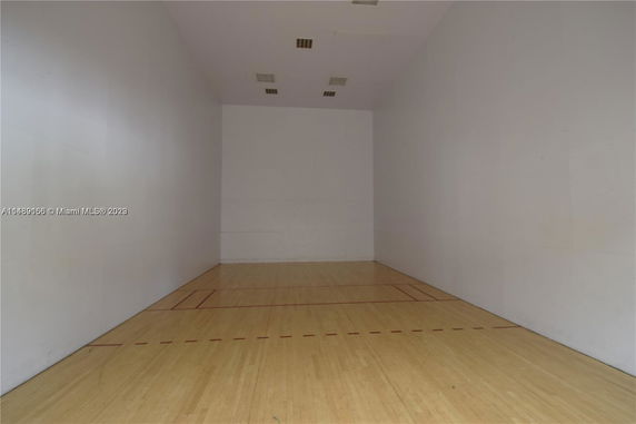 Indoor squash or racquetball court with wooden floor and high walls.