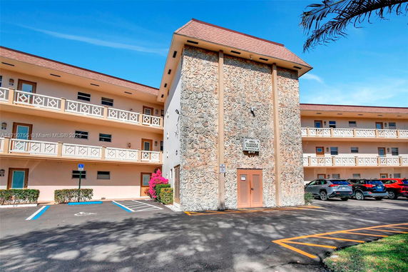 Front view of a multi-story building with stone facade and balconies.