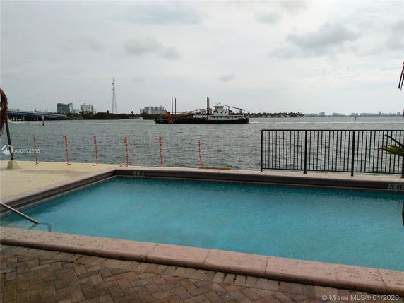 View of a pool near a waterfront with a city skyline in the background.