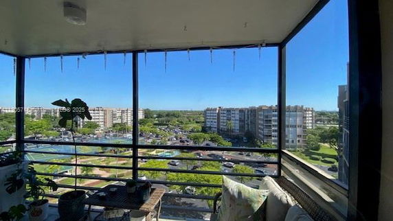 Panoramic view from a building balcony showing surrounding residential buildings and greenery.
