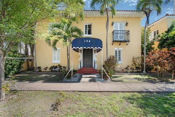 Front view of a two-story house with yellow walls and a blue awning over the entrance.