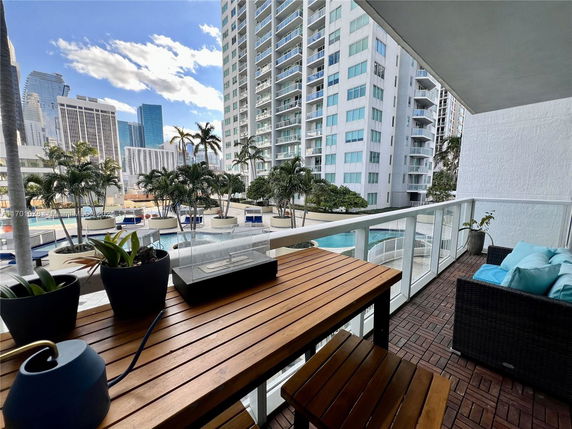 View from a balcony overlooking a pool area with tall buildings in the background.