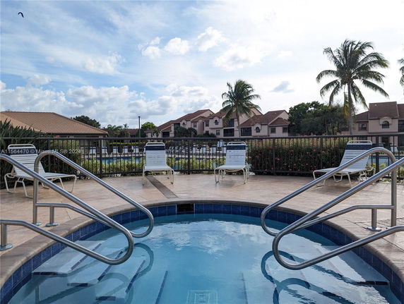 Outdoor swimming pool area with lounge chairs and metal railings.