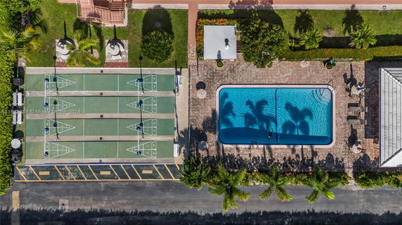 Aerial view of an outdoor area featuring a rectangular swimming pool and adjacent shuffleboard courts.
