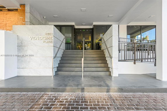 Front view of a building entrance with stairs and glass doors.