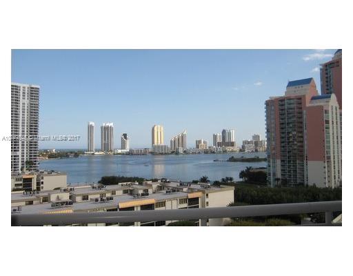 Panoramic view of a cityscape with high-rise buildings and a body of water in the background.