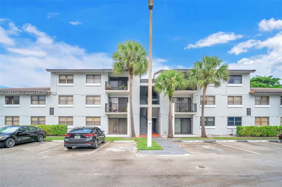 Front view of a three-story apartment building with balconies and parking area.