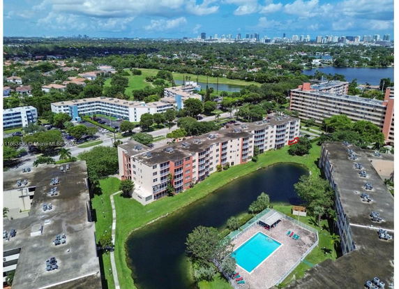 Aerial view of residential buildings with a swimming pool and surrounding landscape.