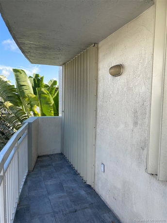 Outdoor balcony view with railing and greenery in the background.
