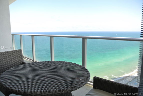 View from a balcony overlooking the ocean and beach below.