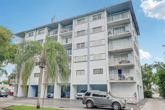 Front view of a multi-story residential building with balconies and parking area.