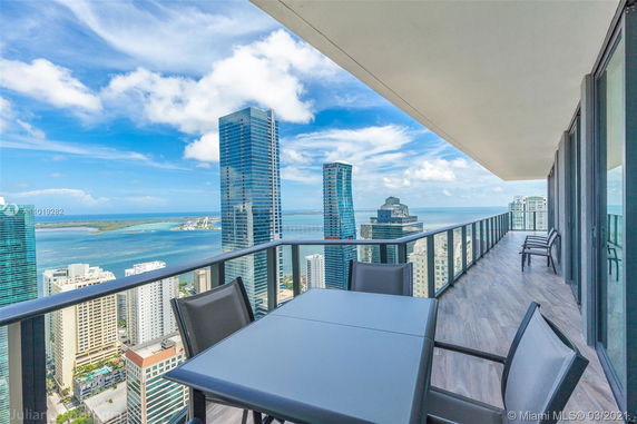 Panoramic view from a high-rise balcony overlooking a city skyline and waterway.