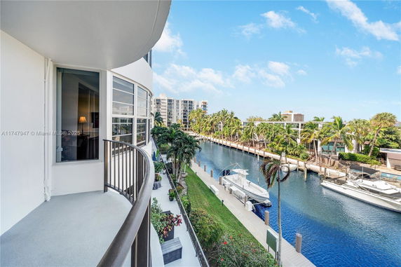 View from a balcony overlooking a canal with boats and palm trees.