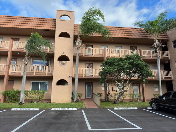 Front view of a three-story apartment building with balconies and a central entrance.