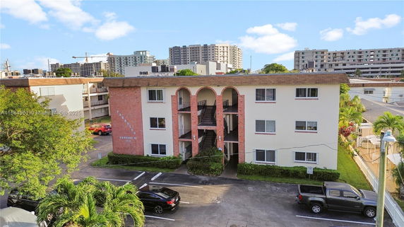 Front view of a multi-story apartment building with brick and white facade.